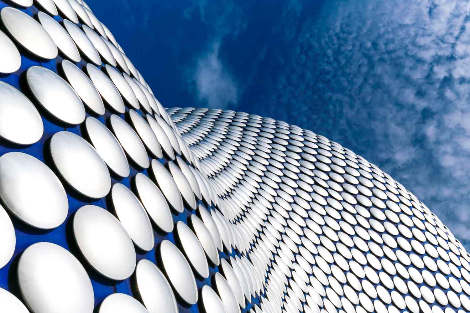 Curved aluminium facade of Selfridges Birmingham against a blue sky
